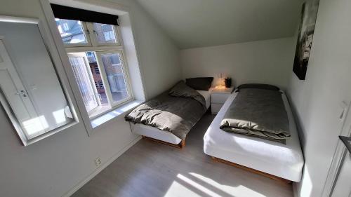 a bedroom with two beds and two windows at Downtown with balcony in Tønsberg