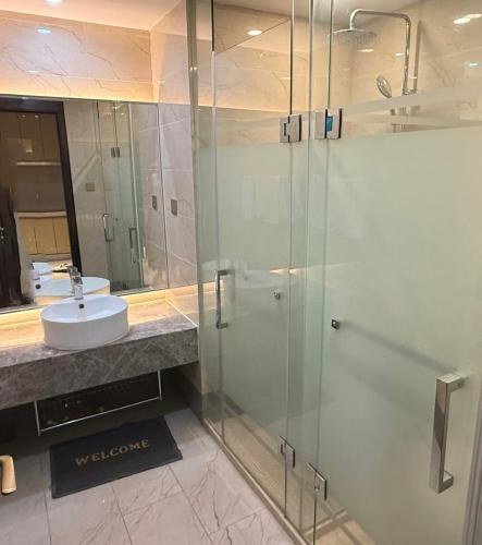 a bathroom with a glass shower and a sink at NAGA Frontier in Vientiane