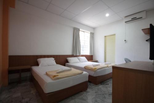 a hotel room with two beds and a television at Bahagia Stay Georgetown in George Town