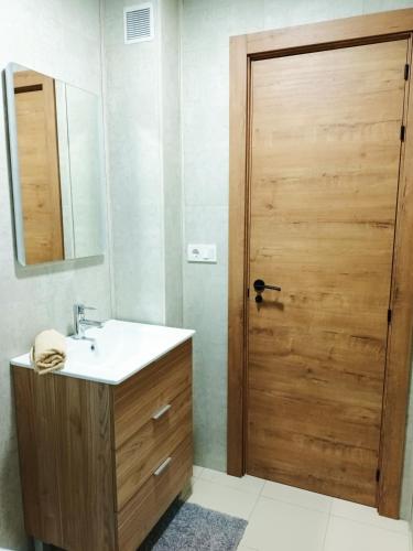 a bathroom with a sink and a wooden door at Apartament La Mata -Maya Bungalow in Torrevieja