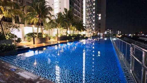 una gran piscina azul en una ciudad por la noche en Seri Alam Cozy Studio by YHA, en Masai