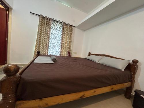 a bedroom with a wooden bed in front of a window at The Mystic Cliff Varkala in Varkala