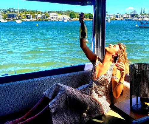 a woman sitting on a boat talking on a cell phone at Liquid PARIDISE Noosaville houseboat "Experience More" in Noosa Heads