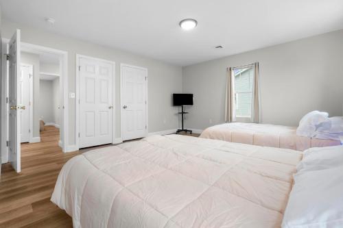 a white bedroom with two beds and a television at Near YALE - Beautiful Waterfront Townhouse in New Haven in New Haven