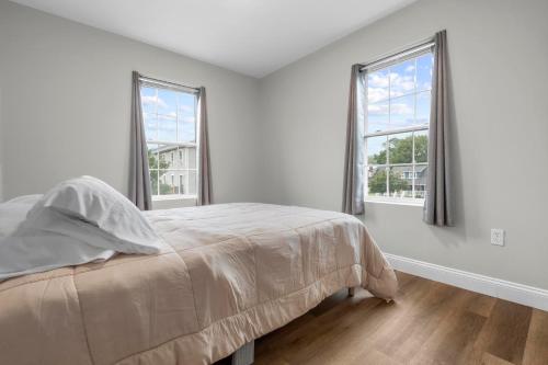 a white bedroom with a bed and two windows at Near YALE - Beautiful Waterfront Townhouse in New Haven in New Haven
