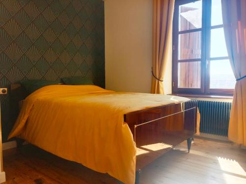 a bedroom with a bed with an orange blanket on it at La petite Maison in Vézézoux