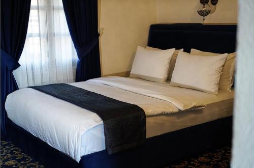 a bedroom with a bed with white sheets and pillows at Rüstempaşa Kervansaray Hotel in Edirne