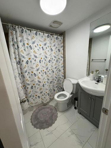a bathroom with a toilet and a sink and a shower curtain at Private Basement Suite in Laval in Laval