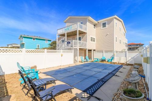 a patio with blue chairs and a house at It's A Vibe in Kitty Hawk