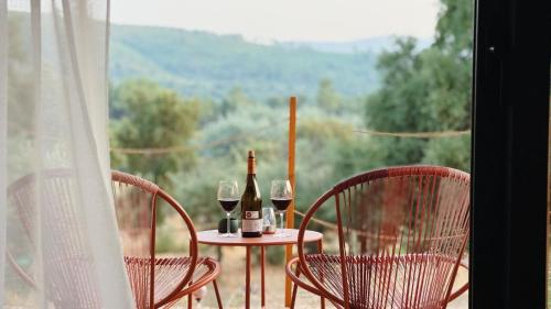 two chairs and a table with wine bottles and glasses at Terras do Salvado Agroturismo in Fundão