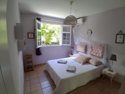 a bedroom with a white bed and a window at Belle Villa 3 chambres piscine Rivière Salée in Rivière-Salée