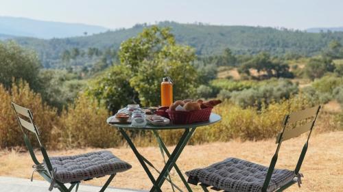 a table with a basket of food and two chairs at Terras do Salvado Agroturismo in Fundão