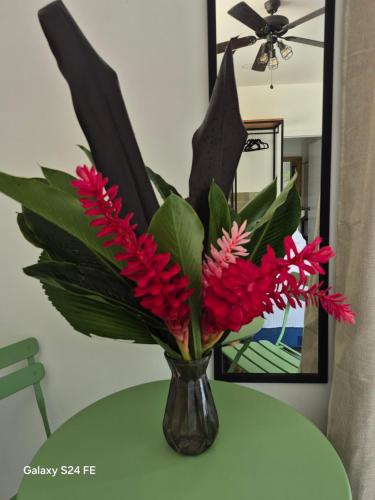 a vase filled with red flowers on a table at Villa Esmeralda in Uvita