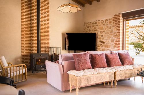 ein Wohnzimmer mit einem rosa Sofa und einem Fernseher in der Unterkunft El Corral de Cayetana in Valdemierque