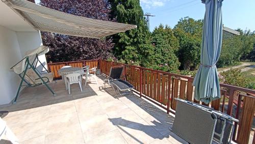 a deck with a table and chairs and a umbrella at Ottó Nyaraló in Révfülöp