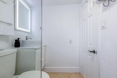 a white bathroom with a toilet and a sink at MIA Airport Modern Studio 10 min Downtown Port in Miami