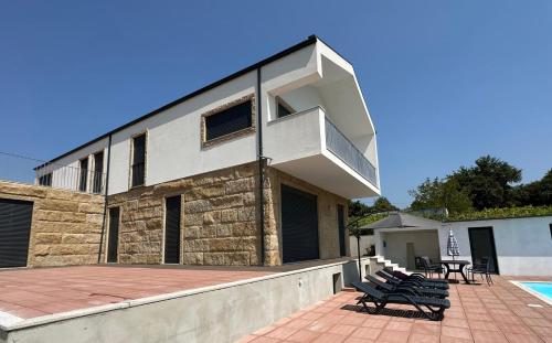 a building with benches on a patio next to a pool at MiraReal Guest House in Macieira da Lixa
