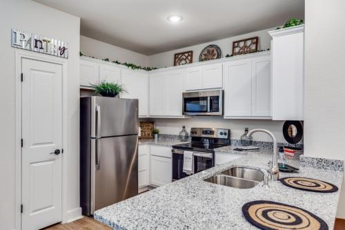 a kitchen with white cabinets and a stainless steel refrigerator at San Antonio Comfort 3 Beds, 2 Baths in Helotes
