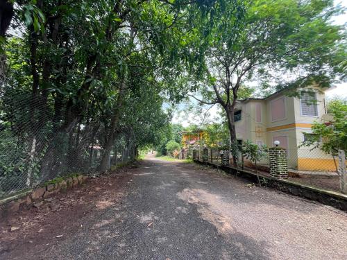 a dirt road with a fence and a house at Aakash Bungalow-EcoFriendlyTourism in Agashi