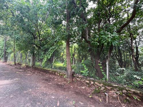 a fence next to a road with trees at Aakash Bungalow-EcoFriendlyTourism in Agashi