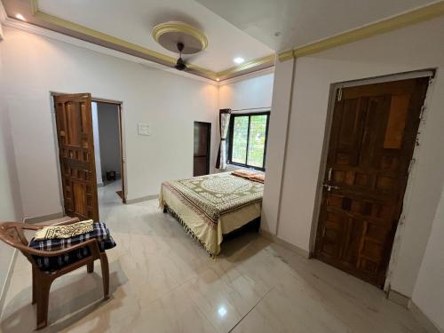 a bedroom with a bed and a chair and a window at Aakash Bungalow-EcoFriendlyTourism in Agashi