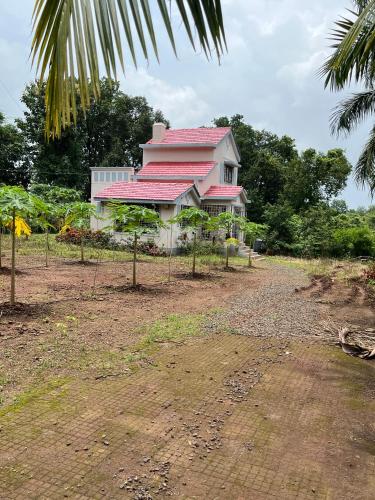 a pink house with a red roof on a field at Aakash Bungalow-EcoFriendlyTourism in Agashi