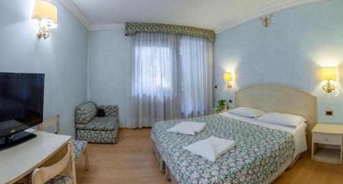 a bedroom with a bed and a chair and a television at Alchimia WellResort in Comano Terme