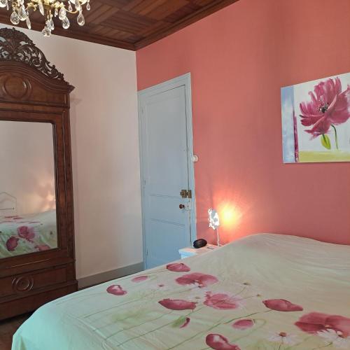 a bedroom with a bed with pink walls and a mirror at La Garenne in Virazeil