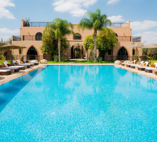 a large swimming pool with chairs and a building at Mwasi Healing and Restoration Center in Oulad Akkou