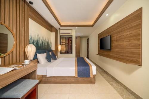 a bedroom with a bed and a desk and a tv at Southern Hotel in Hoi An
