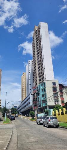 a city street with cars parked in front of tall buildings at Panama City Full apartment 20th floor with a view of the sea and mountains in Panama City