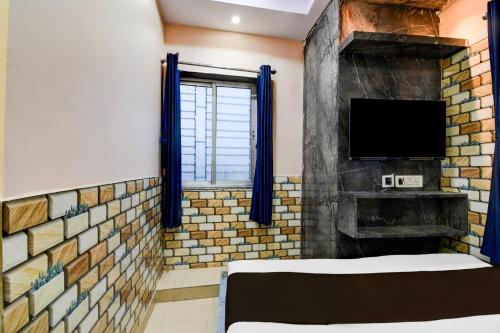 a room with a brick wall and a tv at Hotel O Sana in Calcutta Bara Bazar