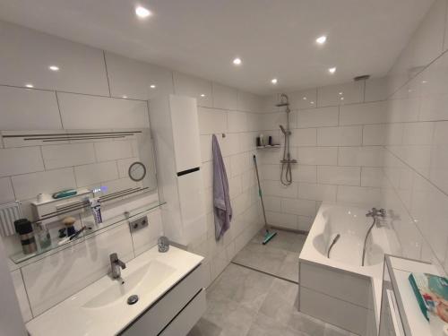 a white bathroom with a tub and a sink at Deluxe Apartment mit 3 Schlafzimmern Hauptbahnhof und zentrumsnah in Oberhausen