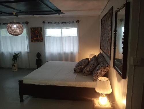 a bedroom with a bed with pillows and a lamp at Casa Del Artista in Ukunda