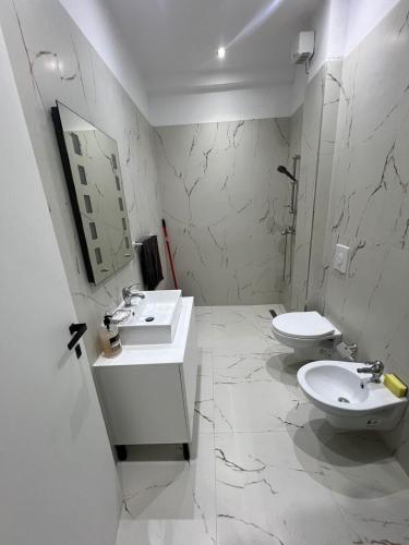 a white bathroom with two sinks and a toilet at Eldi's Home in Vlorë