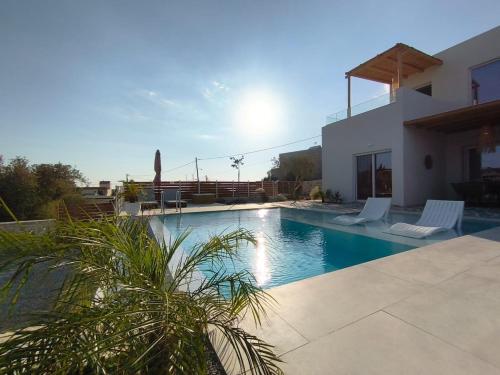 a swimming pool with two chairs and a house at Villa Livia- panoramic view with pool and beautiful garden in Pitsidia