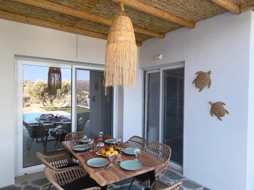 a dining room with a table and chairs and a chandelier at Villa Livia- panoramic view with pool and beautiful garden in Pitsidia