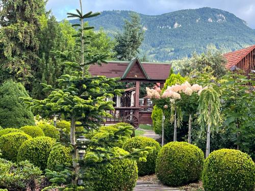 a garden with bushes and a house in the background at Holiday Resort Švárny in Ružomberok