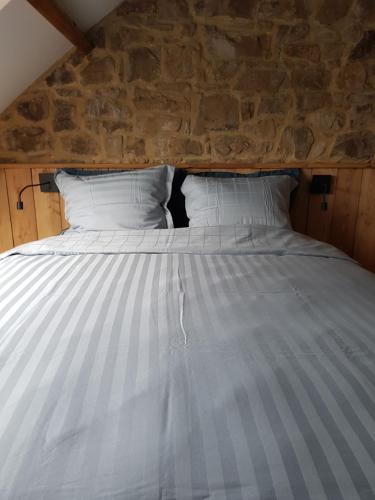 a large bed in a room with a stone wall at Abri du fûret in Lustin