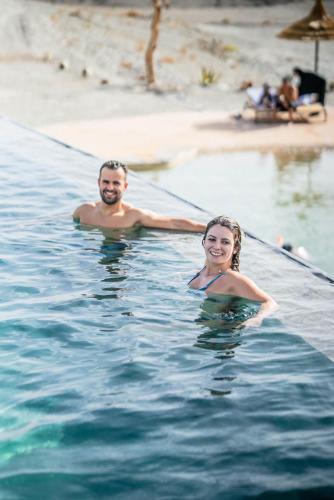 a man and woman in the water at a beach at The seven saints - luxury camp - lodges & tents - desert activities in El Karia