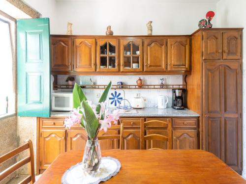 a kitchen with wooden cabinets and a table with flowers at Holiday Home in Arcozelo with Private Pool in Ponte de Lima