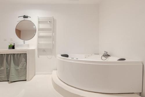 Baño blanco con bañera y espejo en La Petite Bégude Design & Spa, en La Bégude-de-Mazenc