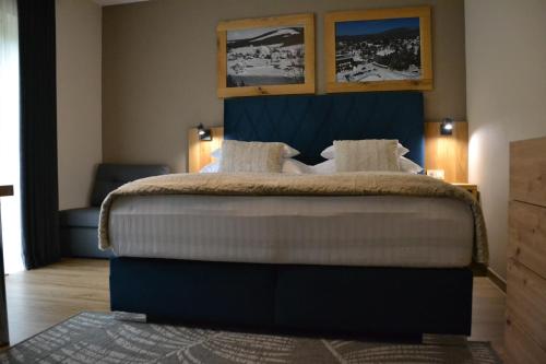 a bedroom with a large bed with a blue headboard at Apartmány Špacír celý dům in Harrachov