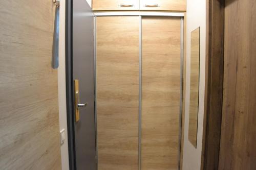 a metal door in a room with a wooden wall at Apartmány Špacír celý dům in Harrachov