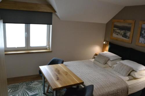 a bedroom with a bed and a wooden table at Apartmány Špacír celý dům in Harrachov