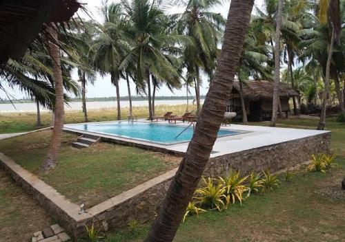 a swimming pool in front of a resort with palm trees at Genge Lake Resort - Kalpitiya in Pallivasalturai