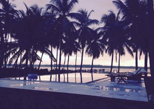 a view of a pool with palm trees and the ocean at Genge Lake Resort - Kalpitiya in Pallivasalturai
