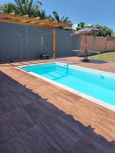 a swimming pool with a wooden deck and an umbrella at Chácara Baruk in Iranduba