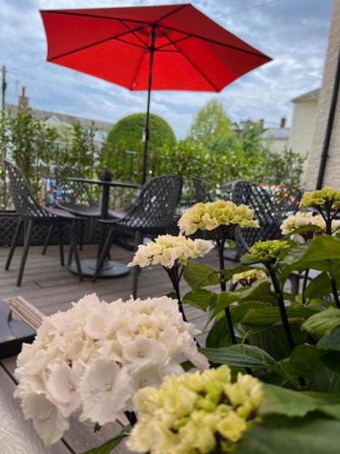 a table with a red umbrella and white flowers at Colcombe Castle Hotel in Colyton