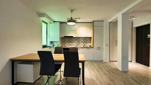 a kitchen with a wooden table and black chairs at Timisoara Prime Residence - powered by NEO - private parking in Timişoara